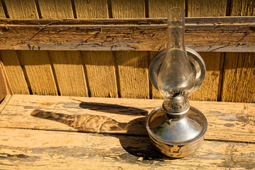 old kerosene lamp stands on wooden surface, outdoors