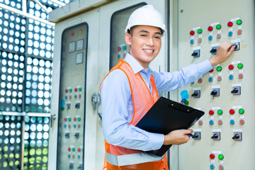 Asian technician at panel on construction site