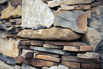 Close view of a rough mediterranean stone wall as background.
