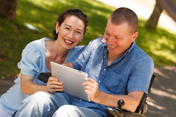 Disabled Man with his wife having fun while using tablet at the