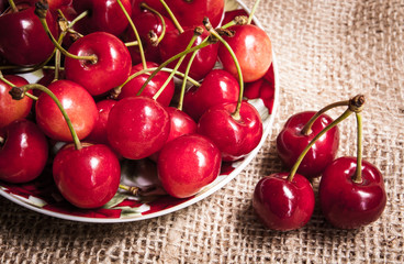 Healthy organic vegetarian super food cherries in clay dish on rustic kitchen table background. Dark photo, rustic style, natural light