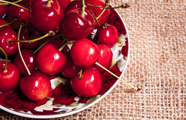 Healthy organic vegetarian super food cherries in clay dish on rustic kitchen table background. Dark photo, rustic style, natural light
