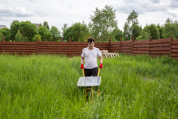 man with empty wheelbarrow in the grass