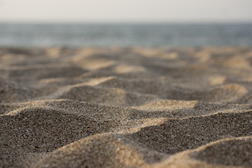 Fototapeta na wymiar El arena de la playa brilla bajo el sol de medio día: Como si fuesen dunas de un desierto, las arenas de la playa brillan bajo el lente macro.