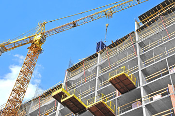 Crane and building construction site against blue sky