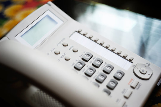 Modern executive VoIP desk phone with traditional corded headset. Shallow depth of field - focus on the center of the image.