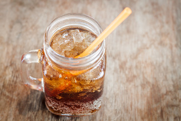 Glass of cola with ice on wooden table