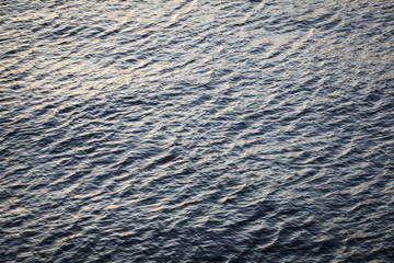 Water surface with ripples and sunrays reflection