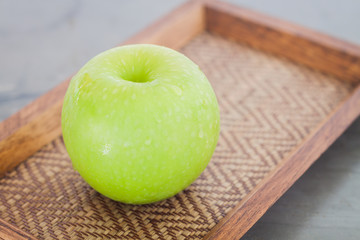 Green apple on wooden tray
