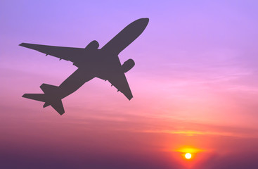 Silhouetted commercial airplane flying at sunset