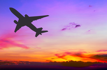 Silhouetted commercial airplane flying at sunset