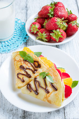 Pancakes with sliced strawberries and orange