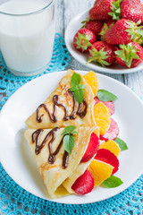Pancakes with sliced strawberries and orange