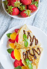 Pancakes with sliced strawberries and orange
