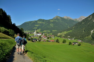 Fototapeta na wymiar Paar erreicht Bergdorf bei Wanderung in Alpen