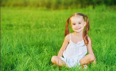 happy child little girl in  white dress lying on grass Summer