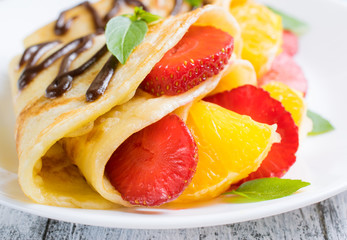 Pancakes with sliced strawberries and orange