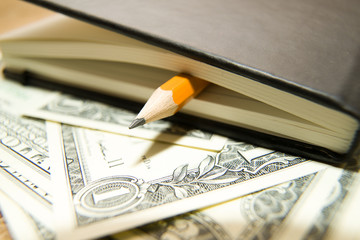 notebook, pencil and money on the old tissue