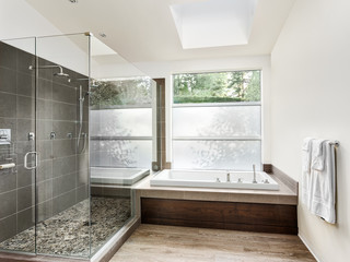 Large furnished bathroom in luxury home with tile floor, fancy cabinets, large mirror, and bathtub