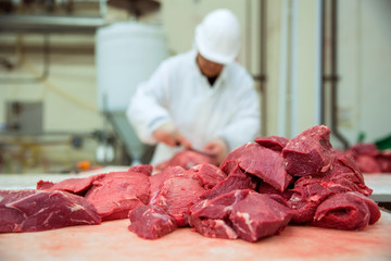 Worker cuts meat butcher handling cuts of prime choice cuts