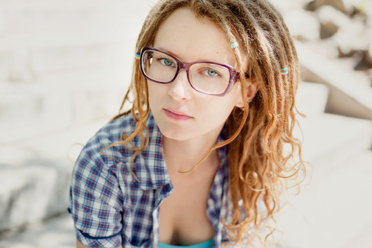 Young stylish girl with dreadlocks outdoors, close-up.