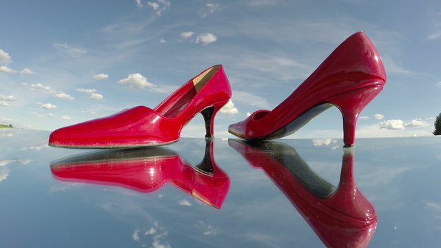 pair red woman shoe stilettos on mirror in space and clouds motion. Fashion concept. Timelapse 4K