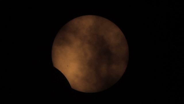 Sun eclipse from the 20.03.2015. with passing clouds - Moon silhouette exiting sun disk. Taken trough my telescope with 1000mm focal length. In the lower left center can be seen a group of sunspots.