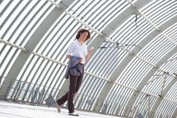 Business woman walking and looking at mobile phone