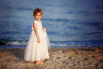 Fototapeta na wymiar girl in a white dress walks on the sea beach