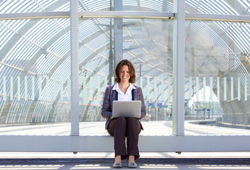 Business woman sitting outside and looking at laptop