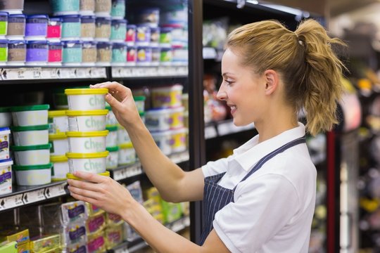 Smiling blonde worker taking a products in shelf 