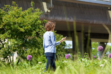 Woman walking in city park looking at her mobile phone