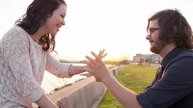 Man proposes in a park overlooking a bay