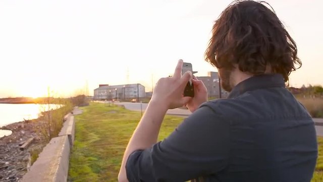 Man taking pictures in a park near a bay