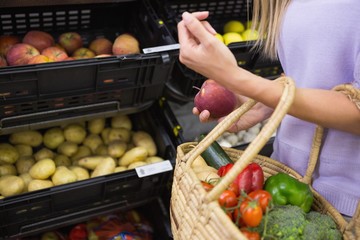Smiling woman taking a fruit in the aisle 