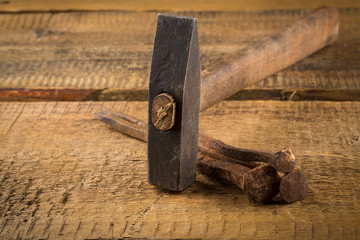 Vintage hammer with nails on wood background