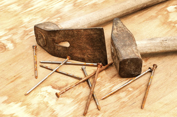 Old weathered grunge hammer and adze head closeup on plywood surface