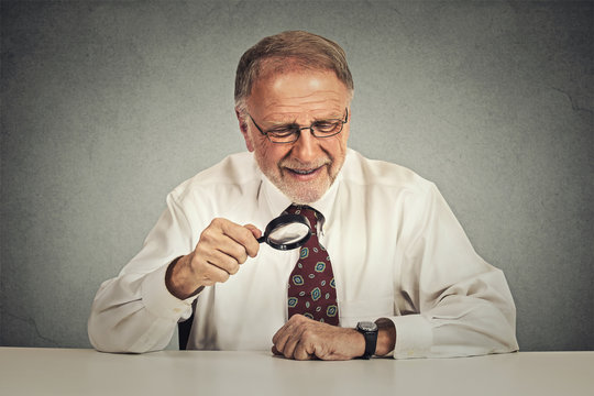 Senior businessman looking through a magnifying glass