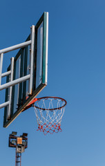 Basketball board and hoop with blue sky background.