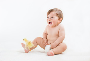 Baby boy in diapers sitting on the floor, playing with cute chick on an isolated white, horizontal...