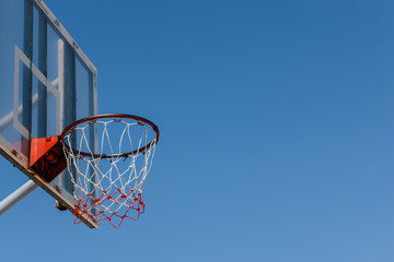 Basketball board and hoop with blue sky.