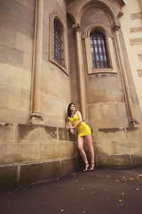 Fototapeta na wymiar beautiful girl in a yellow dress leaned on old architectural bui