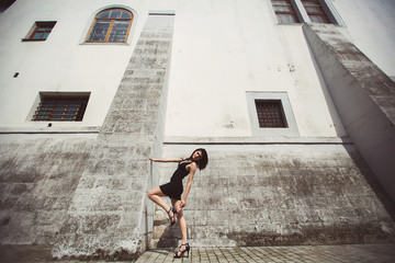 beautiful girl in a black dress stands near architectural struct