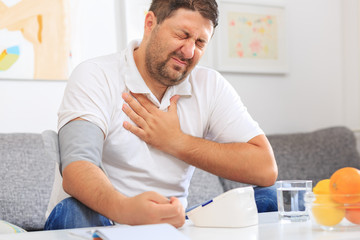 Fototapeta na wymiar Man measuring his blood pressure feeling chest pain