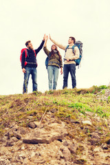 group of smiling friends with backpacks hiking