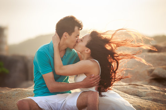 girl and guy kiss against rocks