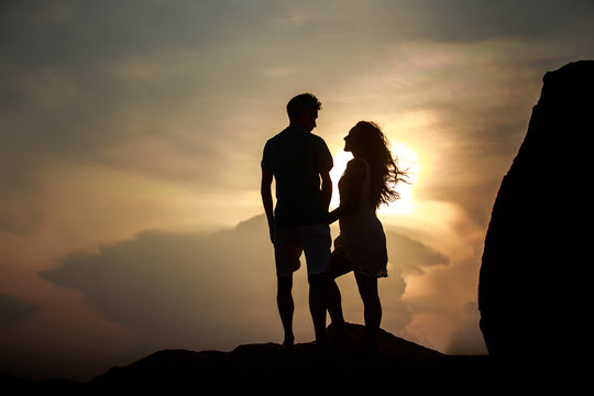 silhouette of kissing guy and girl at dawn