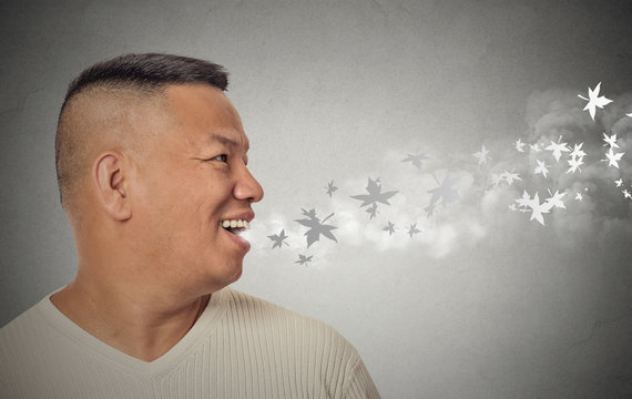 man with open mouth blowing cold breeze snowflakes flying away