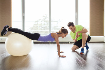 smiling man and woman with exercise ball in gym