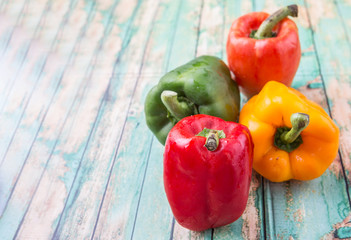 Fresh colorful bell peppers on a rustic wooden background